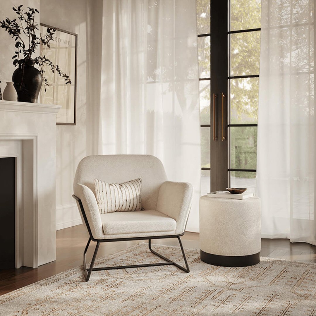 Lifestyle shot of the armchair with a cushion and a pouffe in the same boucle fabric next to it