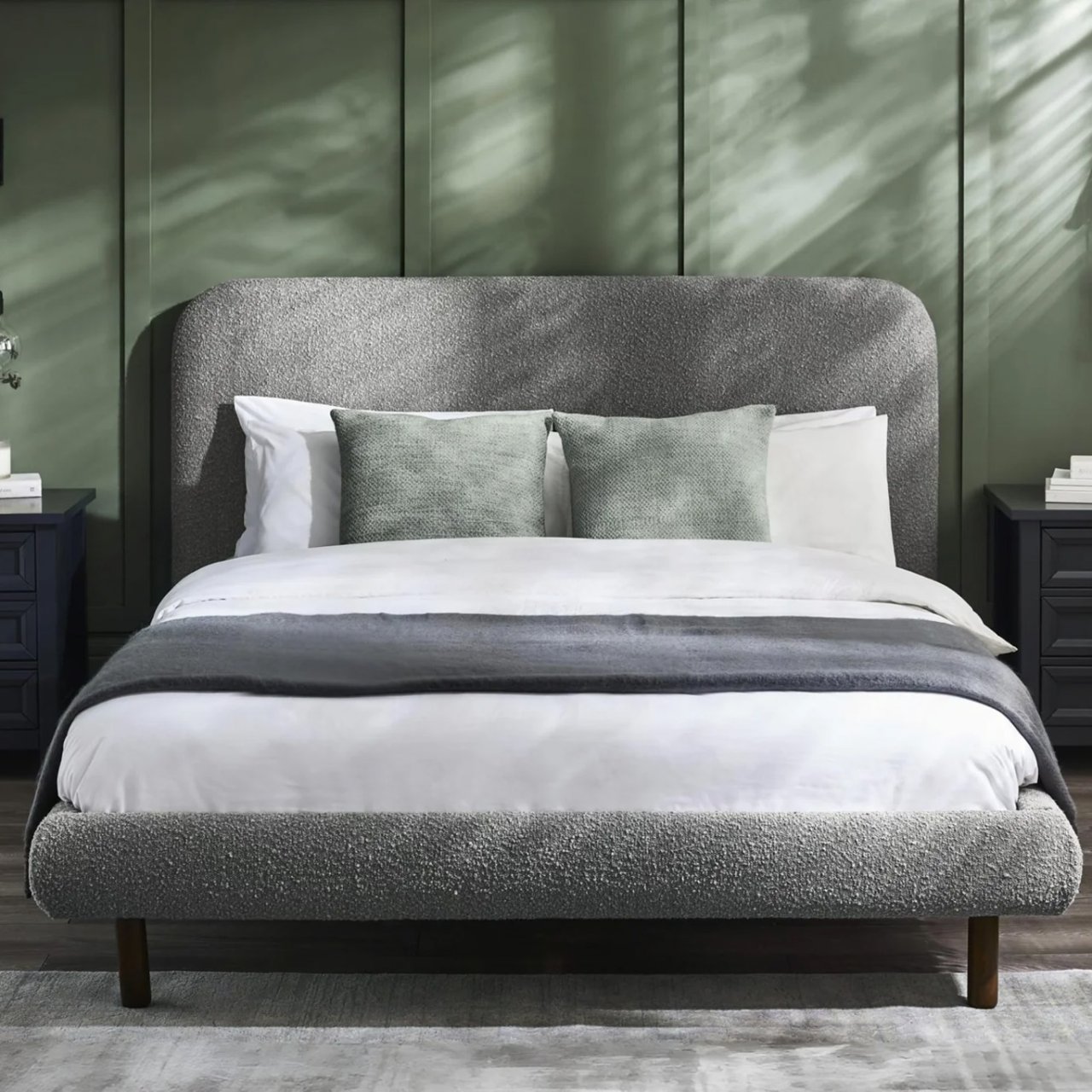 Live shot of the bed in a bedroom with green wooden walls