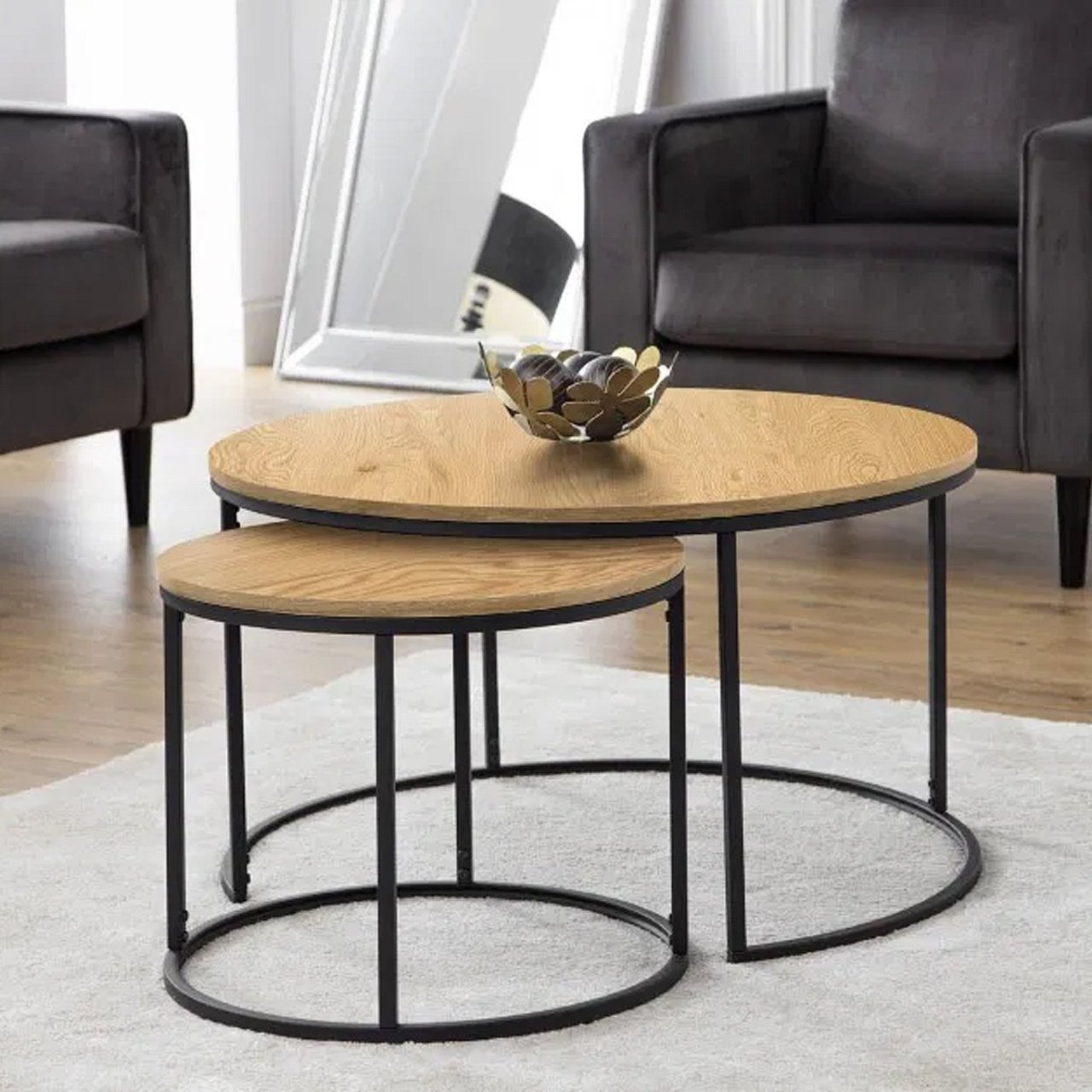 Lifestyle shot of the coffee table set showing them in a staggered arrangement on a white carpet, contrasting with their black metal legs and a lino floor complementing their oak veneer top