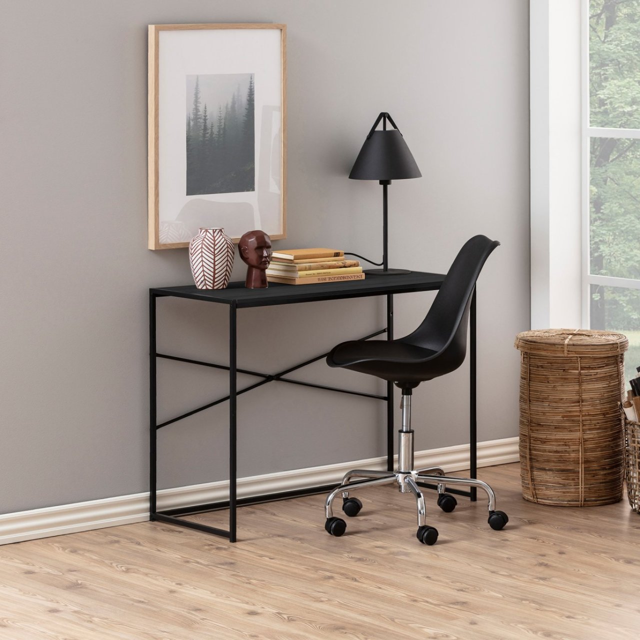 Lifestile shot of the See Desk in black with an office chair next too it and books on top