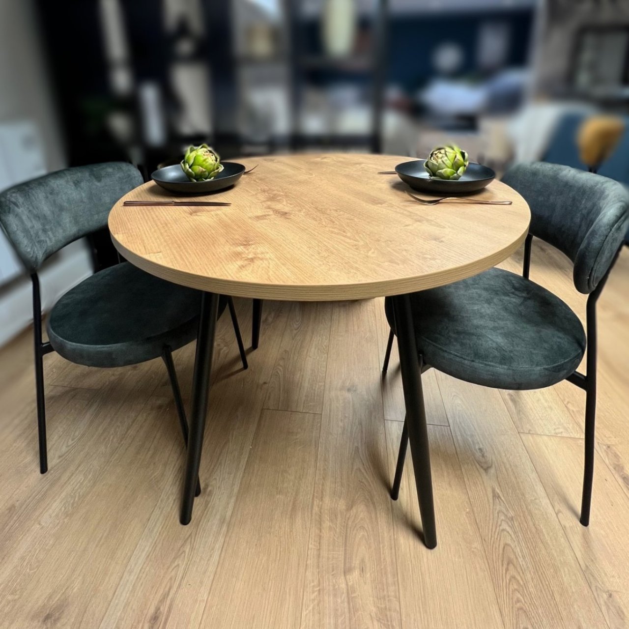 Lifestyle shot of the Balfron dining table with two modern dining chairs upholstered with velvet fabric next to it