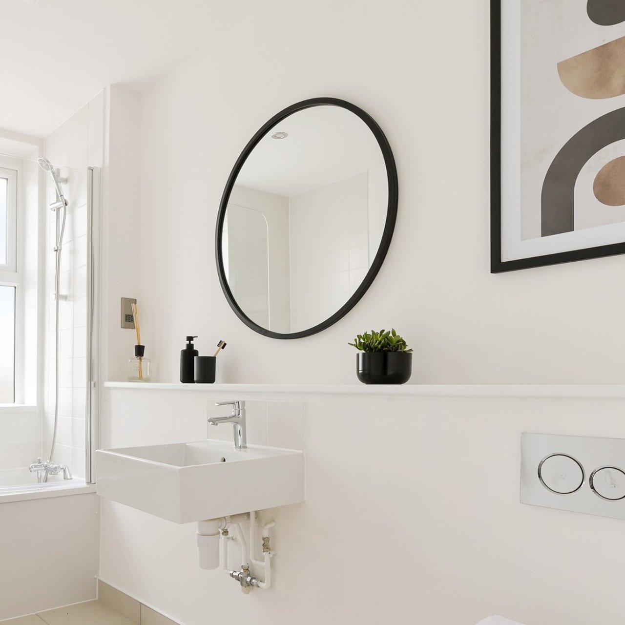 Lifestyle shot of the round mirror with black frame attached to the bathroom wall over a sink