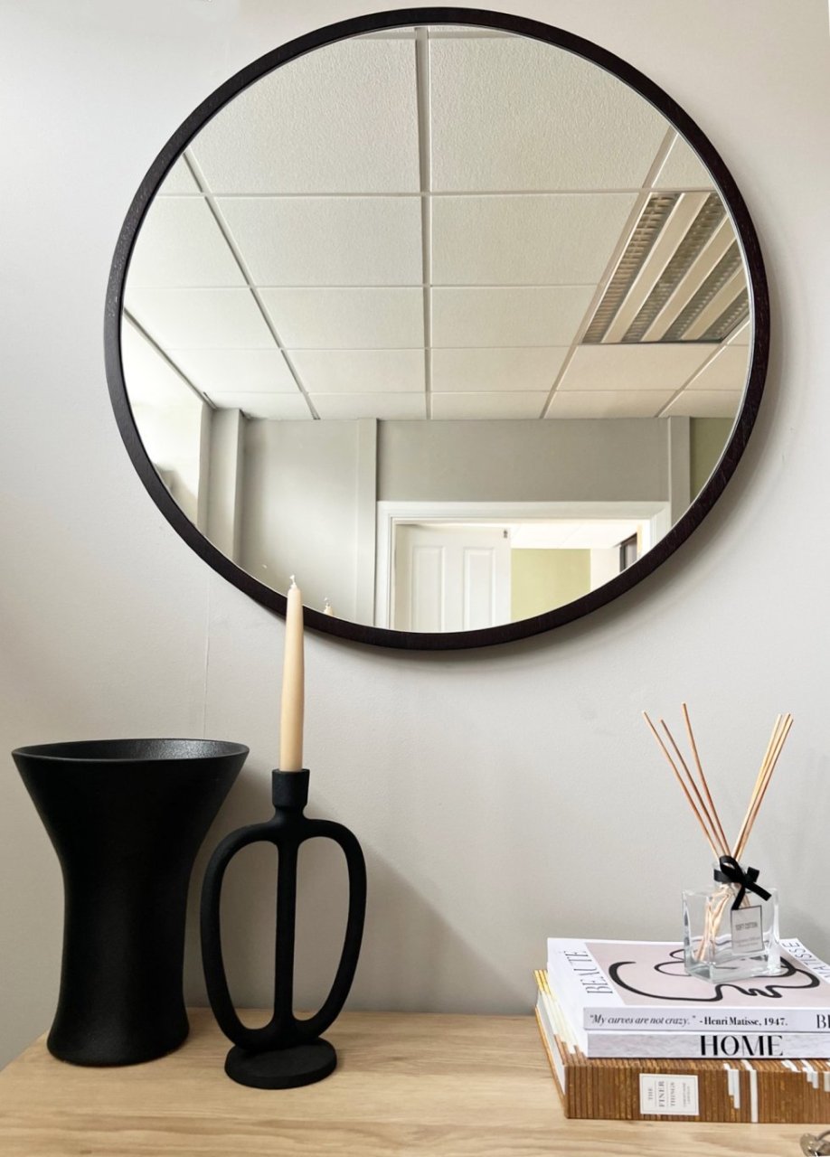 Lifestyle shot of the mirror attached directly to a wall over a decorated chest of drawers