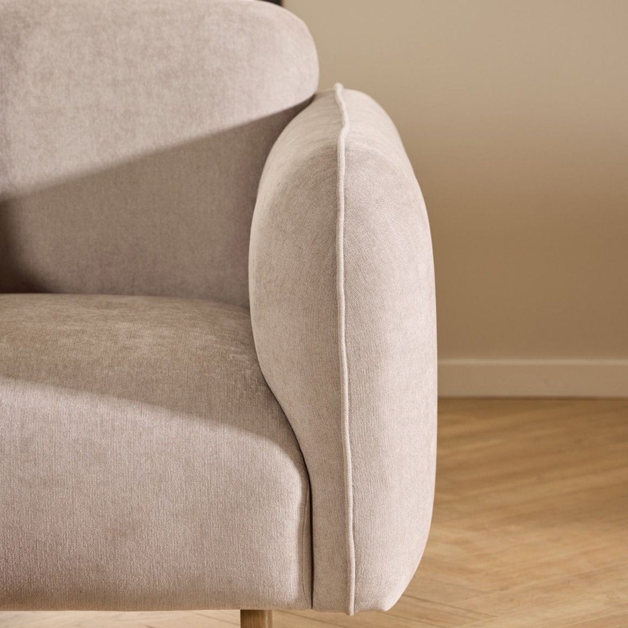 Zoom in on the front right side of the sofa with the depth of the cushion visible as well as one smooth round oak leg in sight