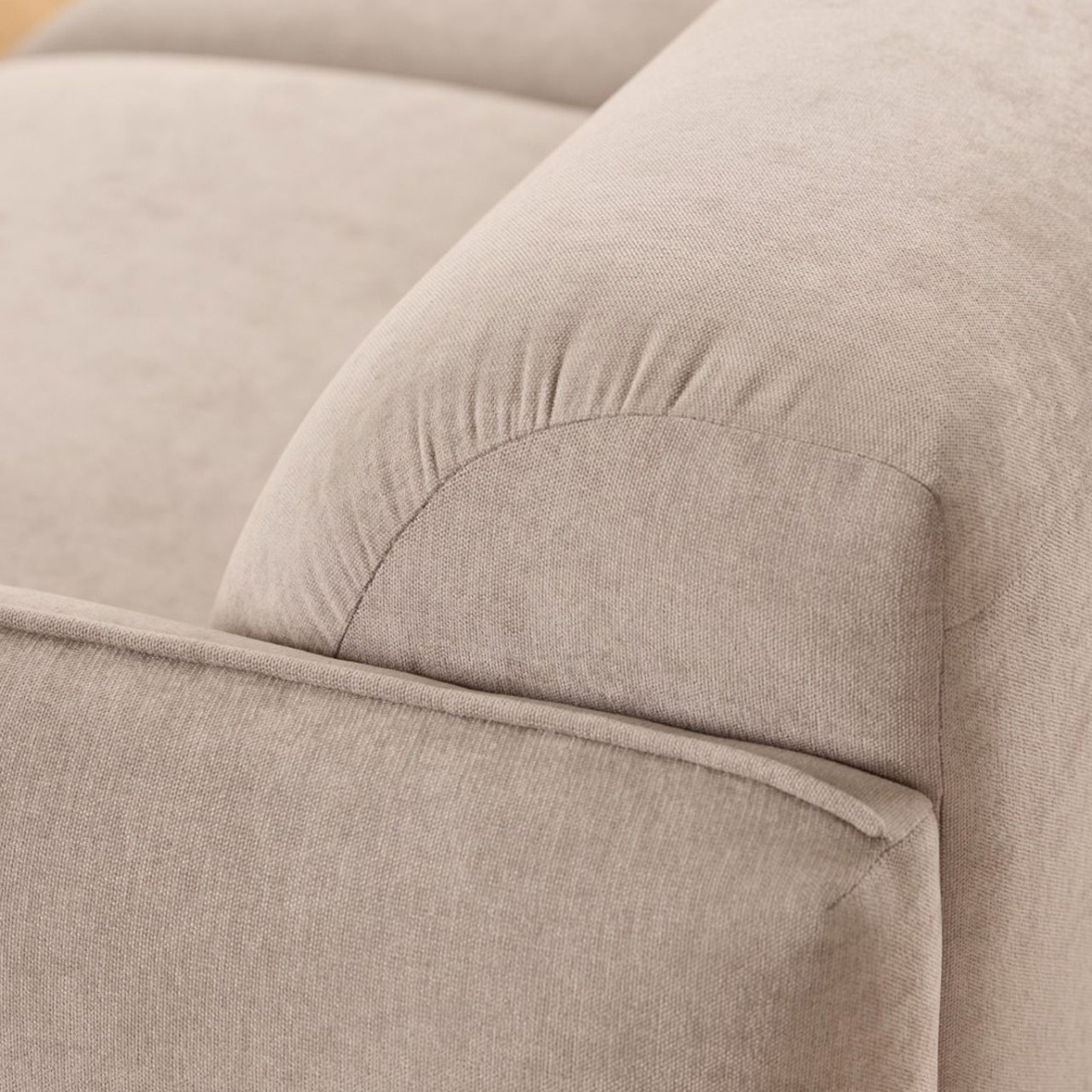 Zoom in on the side of the sofa showing the piped edge of the armrest as well as the sturdy stitching of the back cushions