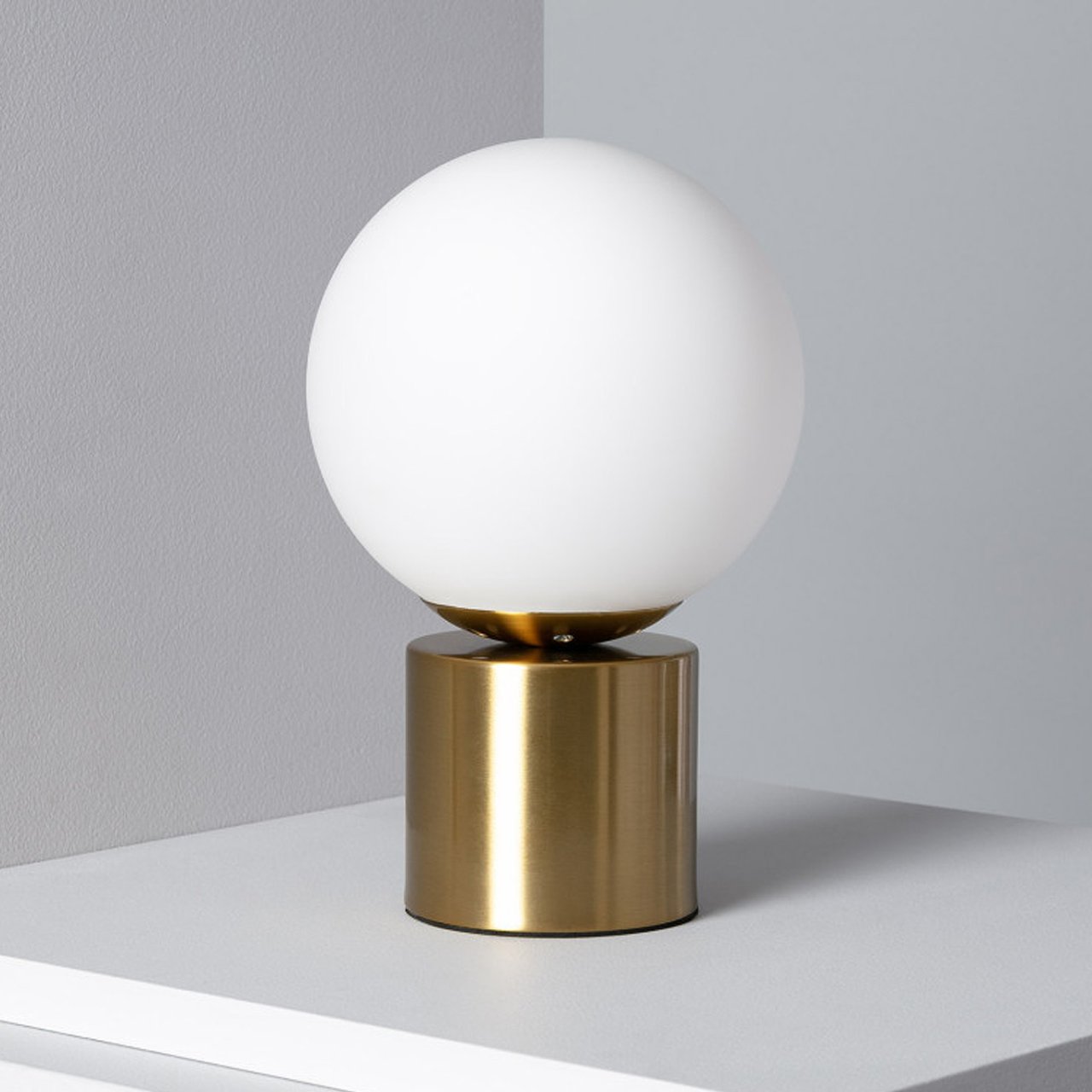 Lamp with a short gold base and white shade