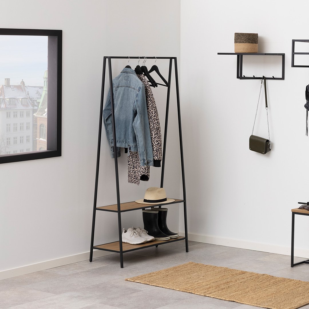 Lifestyle shot of the clothes rack showing jackets hanging on it with a hat and shoes on the shelves