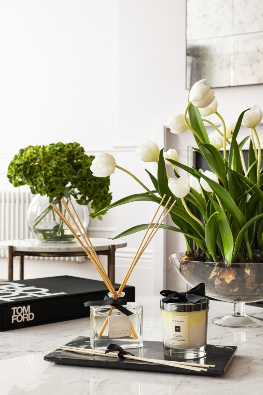 A zoom in of white tulip bulbs, a Jo Malone candle and a soft cotton scent diffuser