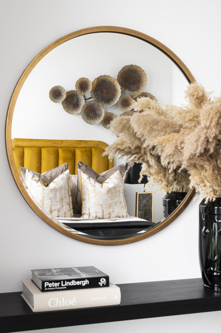 A reflection of a bed with a bright yellow headboard in the mirror. 