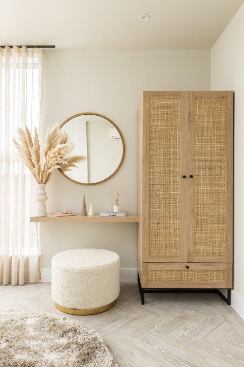2 door wardrobe with rattan finish and a wide stool sitting under a dressing table attached to a wall.